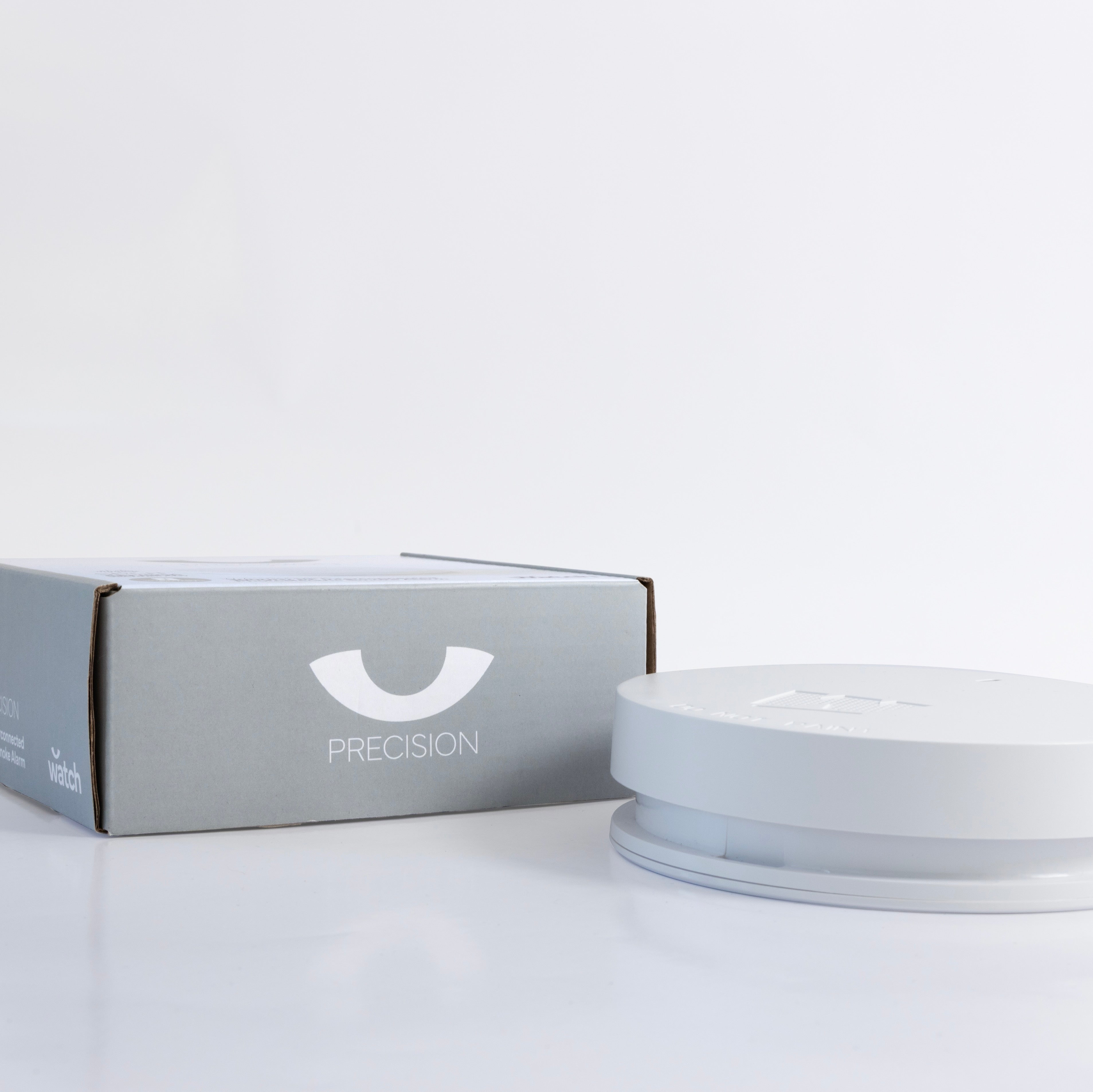 White smoke alarm and box with 'Precision' branding on a light gray background